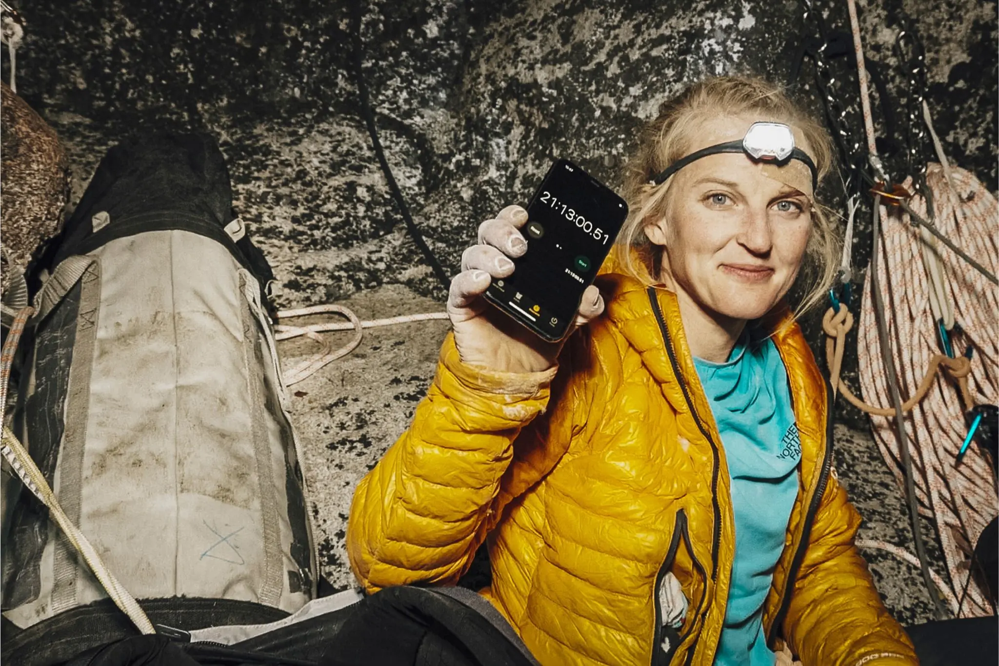 Woman in yellow jacket and headlamp holds up iPhone timer