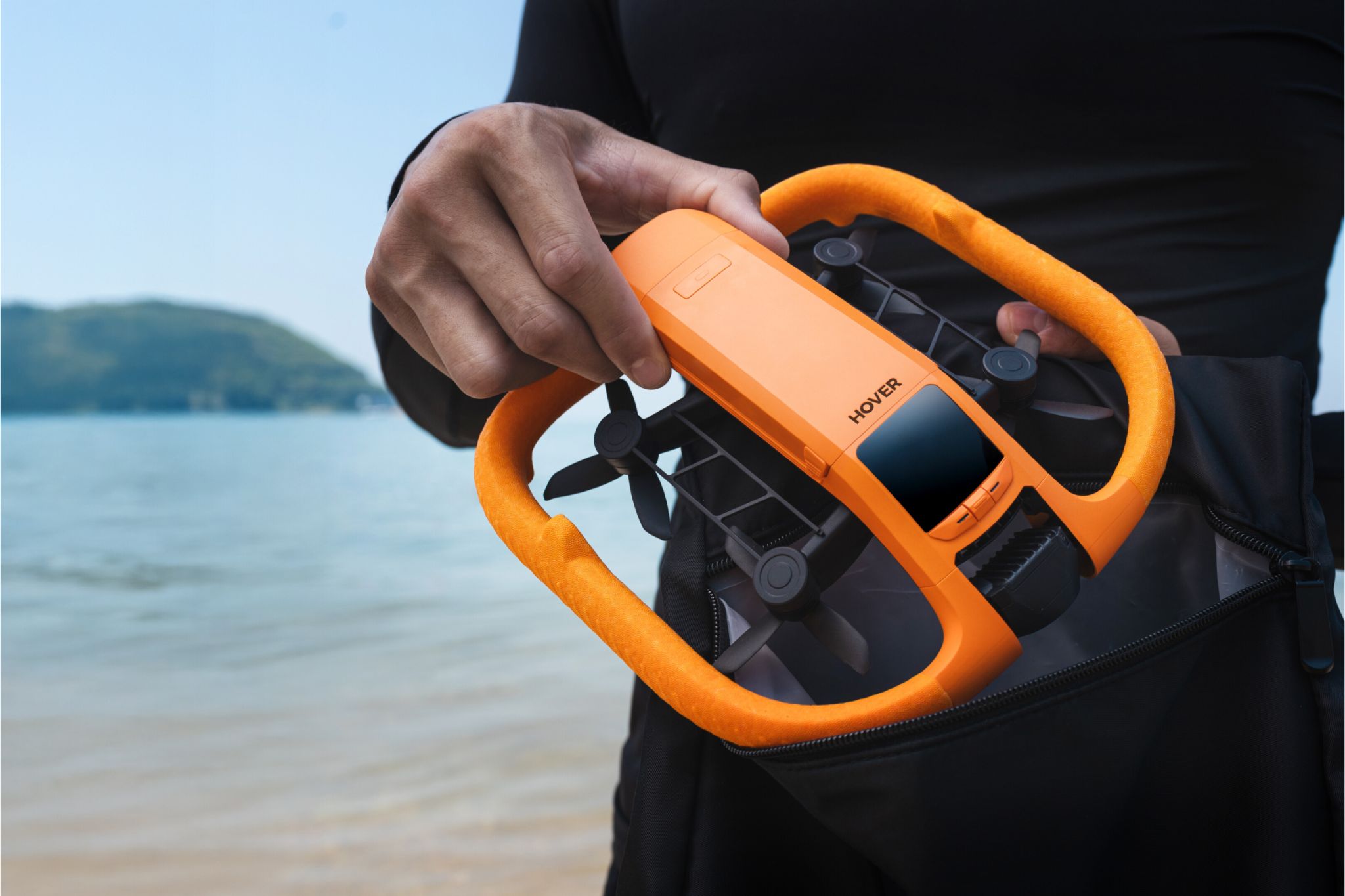 Close up of person holding orange drone on the beach