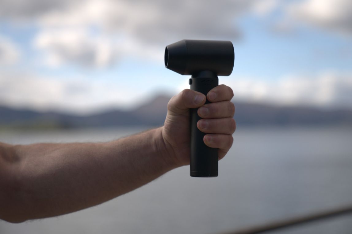 Close up of hand holding small black cordless dryer