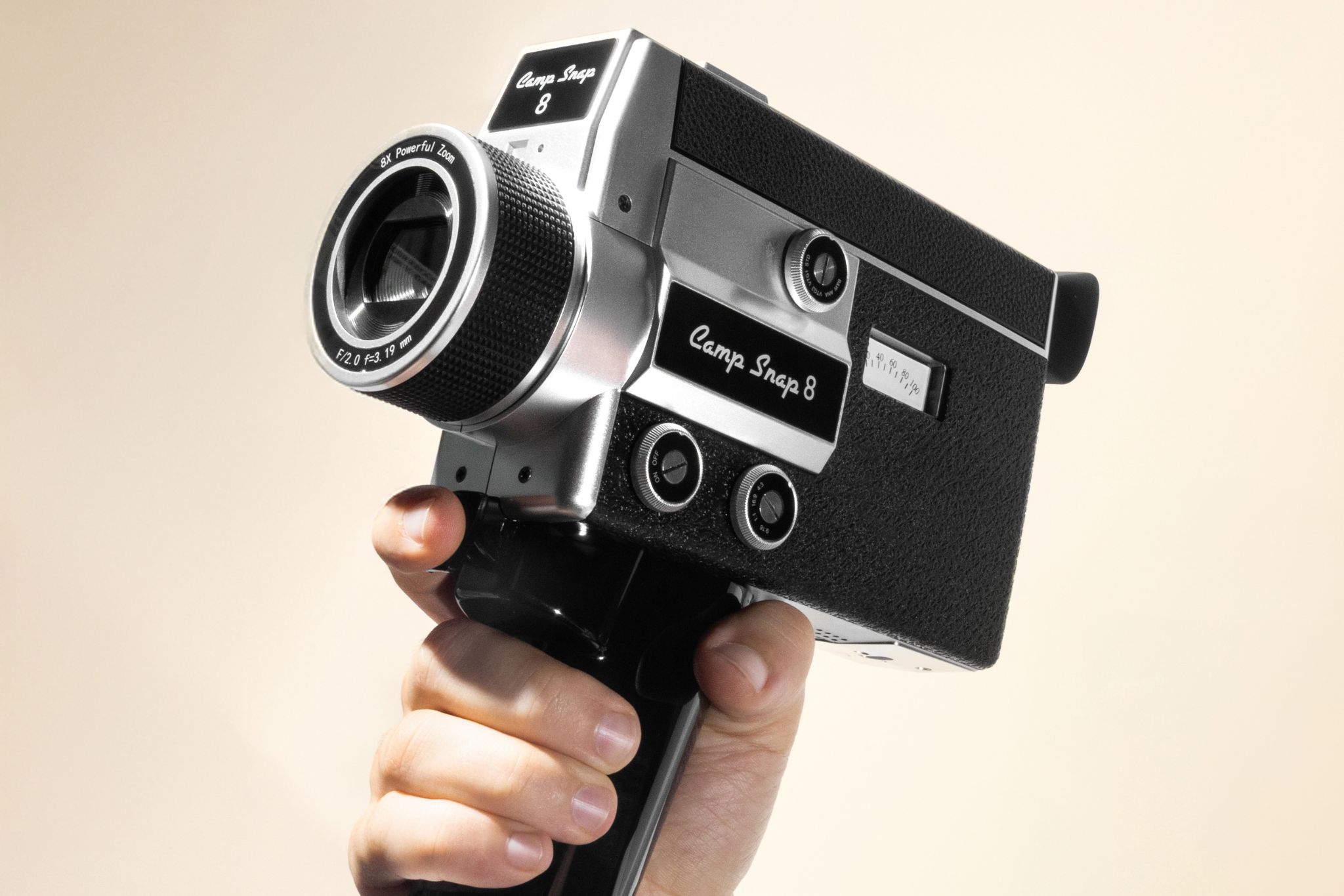 Close up shot of a hand holding a silver and black retro video camera