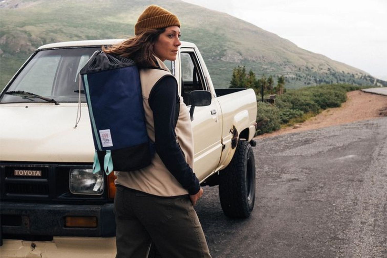 Woman wearing sporty clothes wears blue backpack and walks in front of a truck