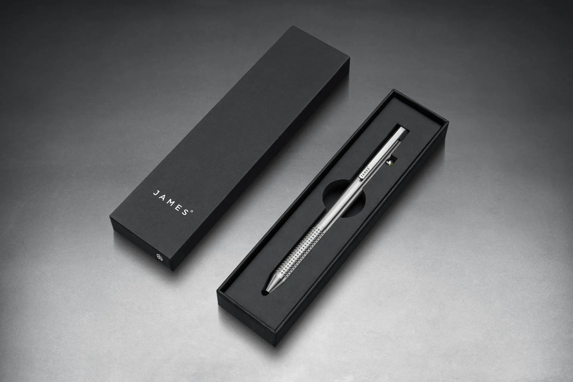 Silver pen in black case on black surface. 