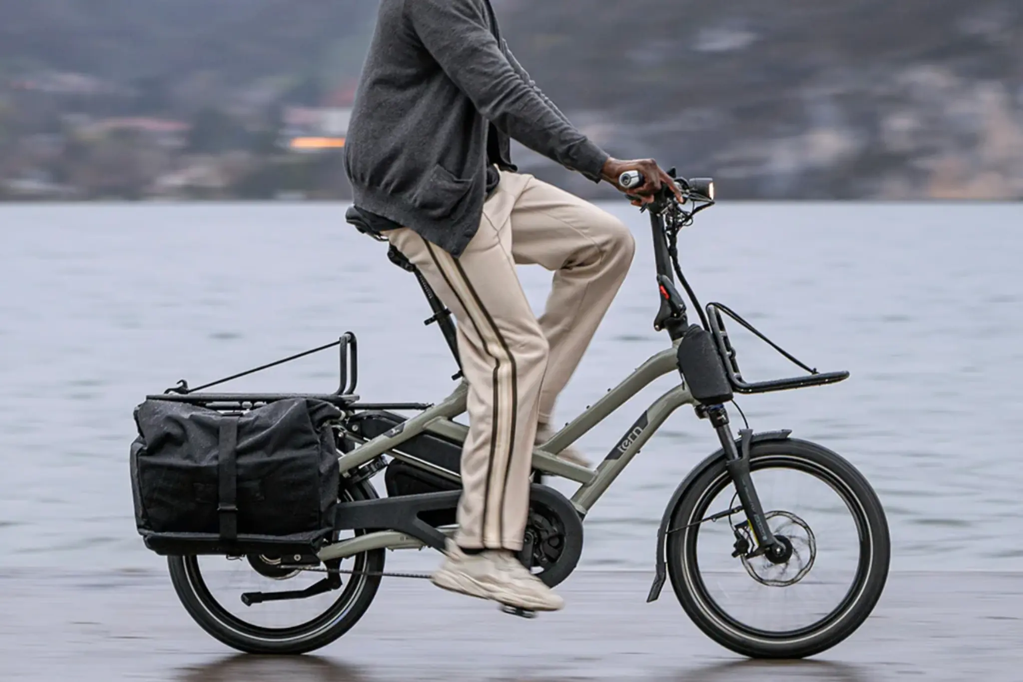 Person rides army green e-bike with bike bag alongside like