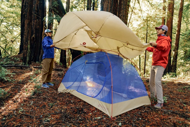 two camper setting a rainfly on a marmot tent
