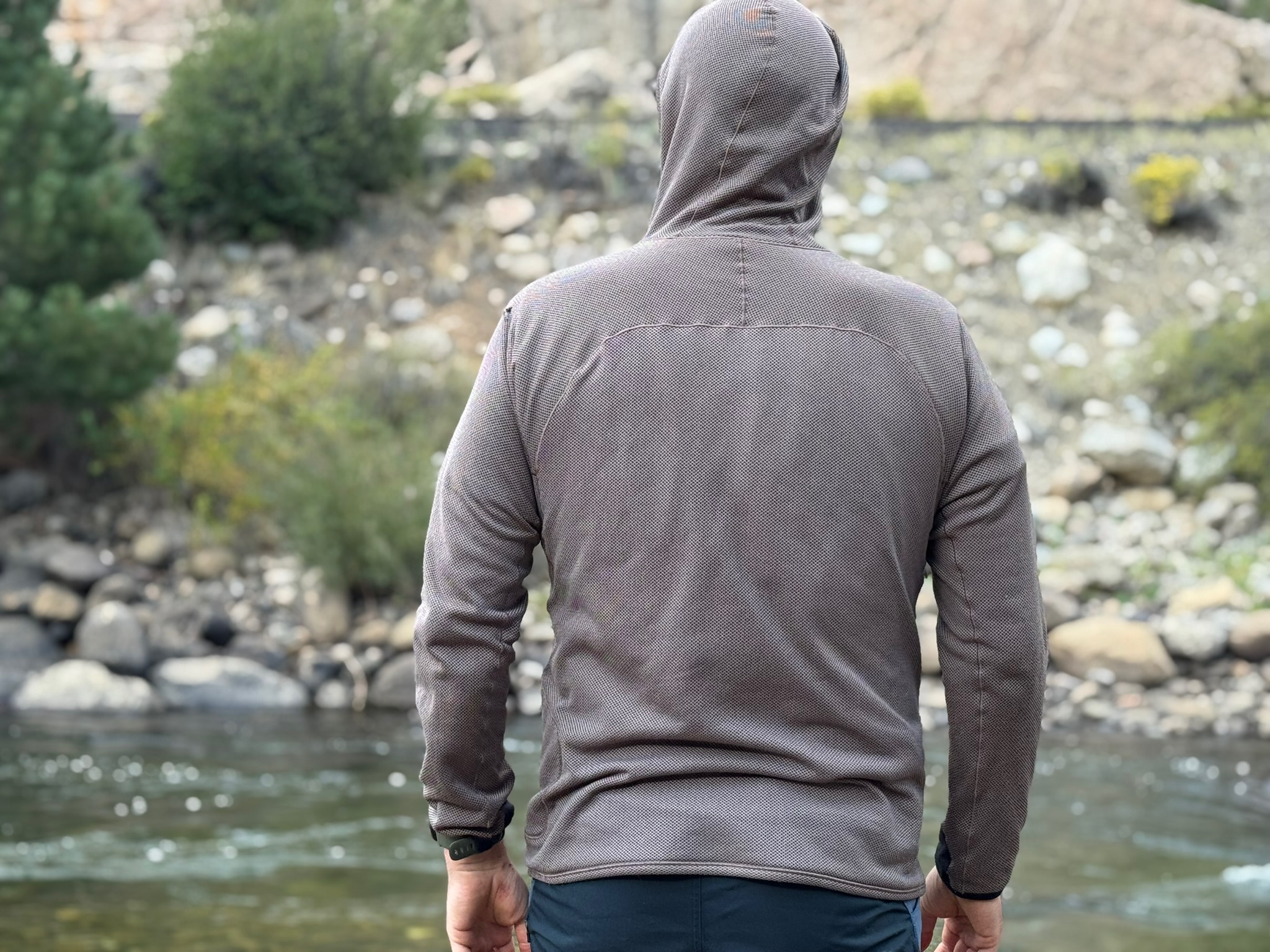 Man wearing the Mountain Hardwear Airmesh Hoody seen from behind near a river