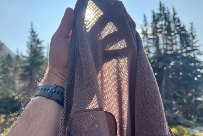 Closeup of the Mountain Hardwear Airmesh Hoody fabric held to the sunlight showing its mesh