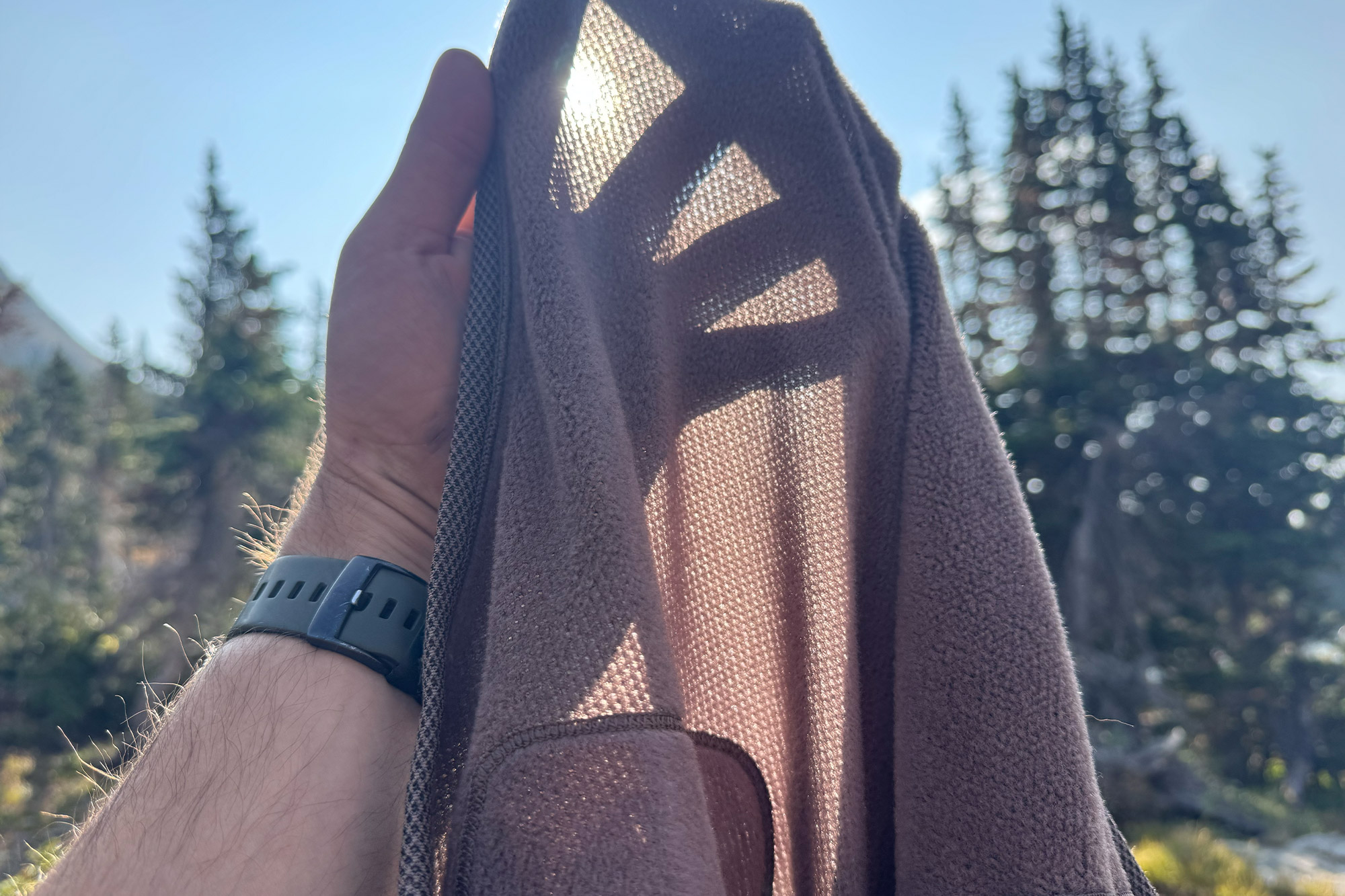 Closeup of the Mountain Hardwear Airmesh Hoody fabric held to the sunlight showing its mesh