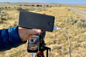 Anker 313 Power Bank charging a phone outdoors next to a camera setup