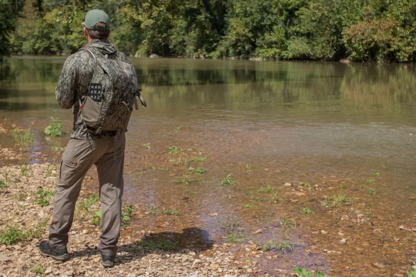 A hunter wearing the Badlands Andaire pants next to a river.