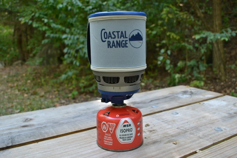 Stove set up on picnic table attached to gas canister.