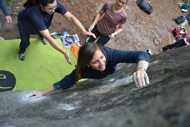 Up close shot of person climbing boulder outside with spotters