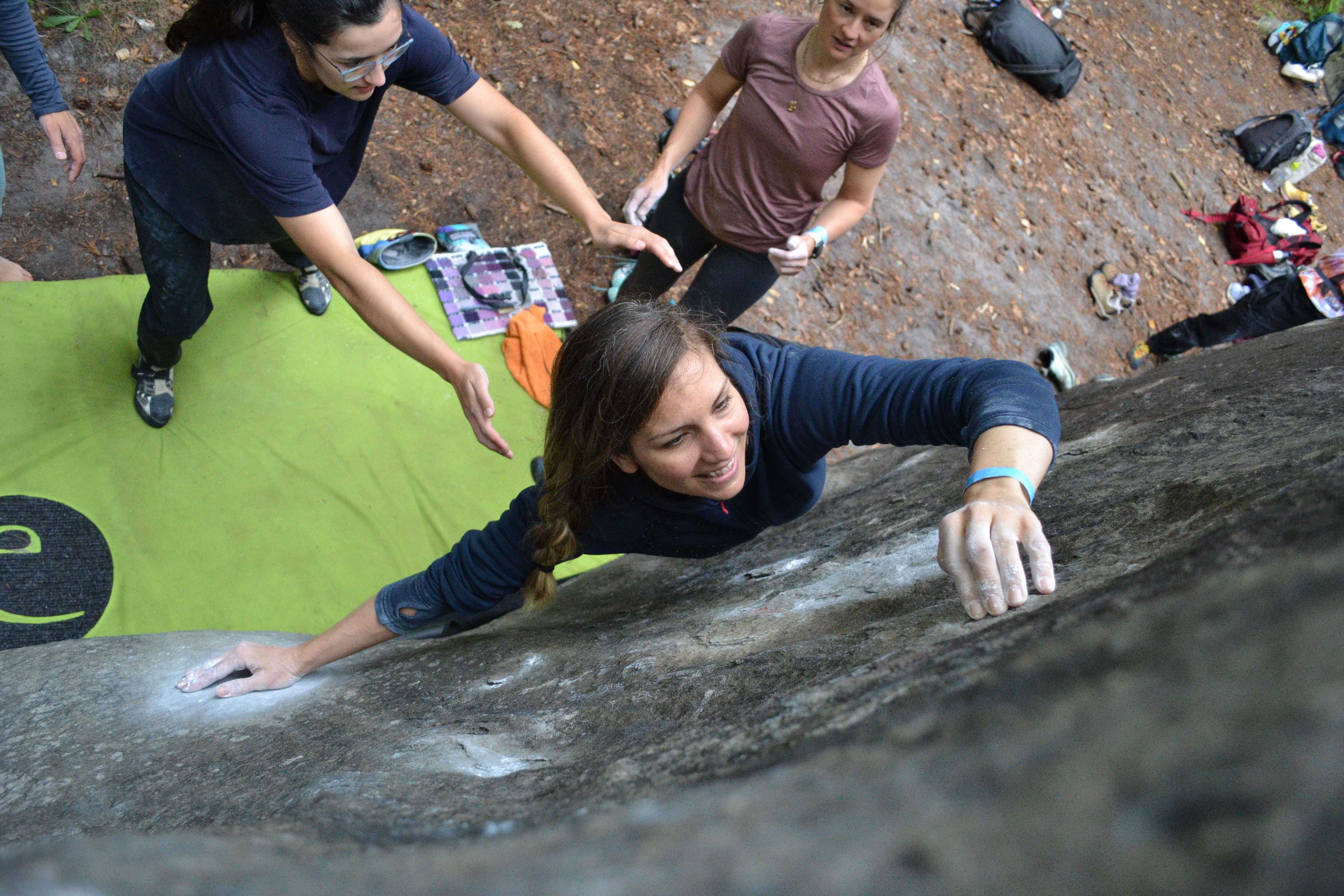 Up close shot of person climbing boulder outside with spotters