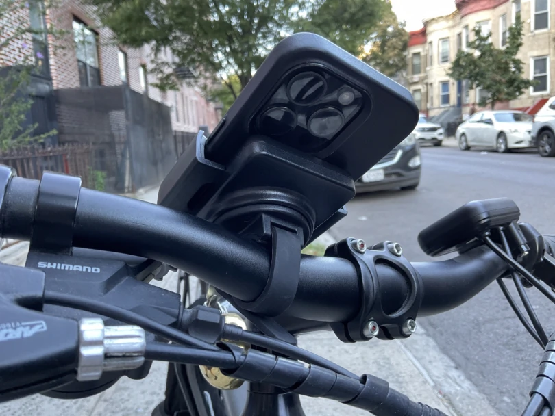 The bottom view of an iPhone 15 Pro on a Nite Ize phone mount on the handlebars of an electric bike.