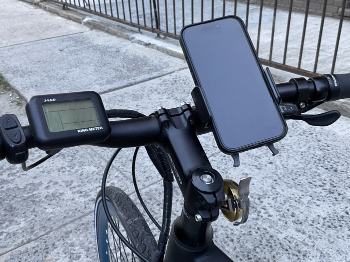 An iPhone 15 Pro on a Nite Ize phone mount on the handlebars of an electric bike.