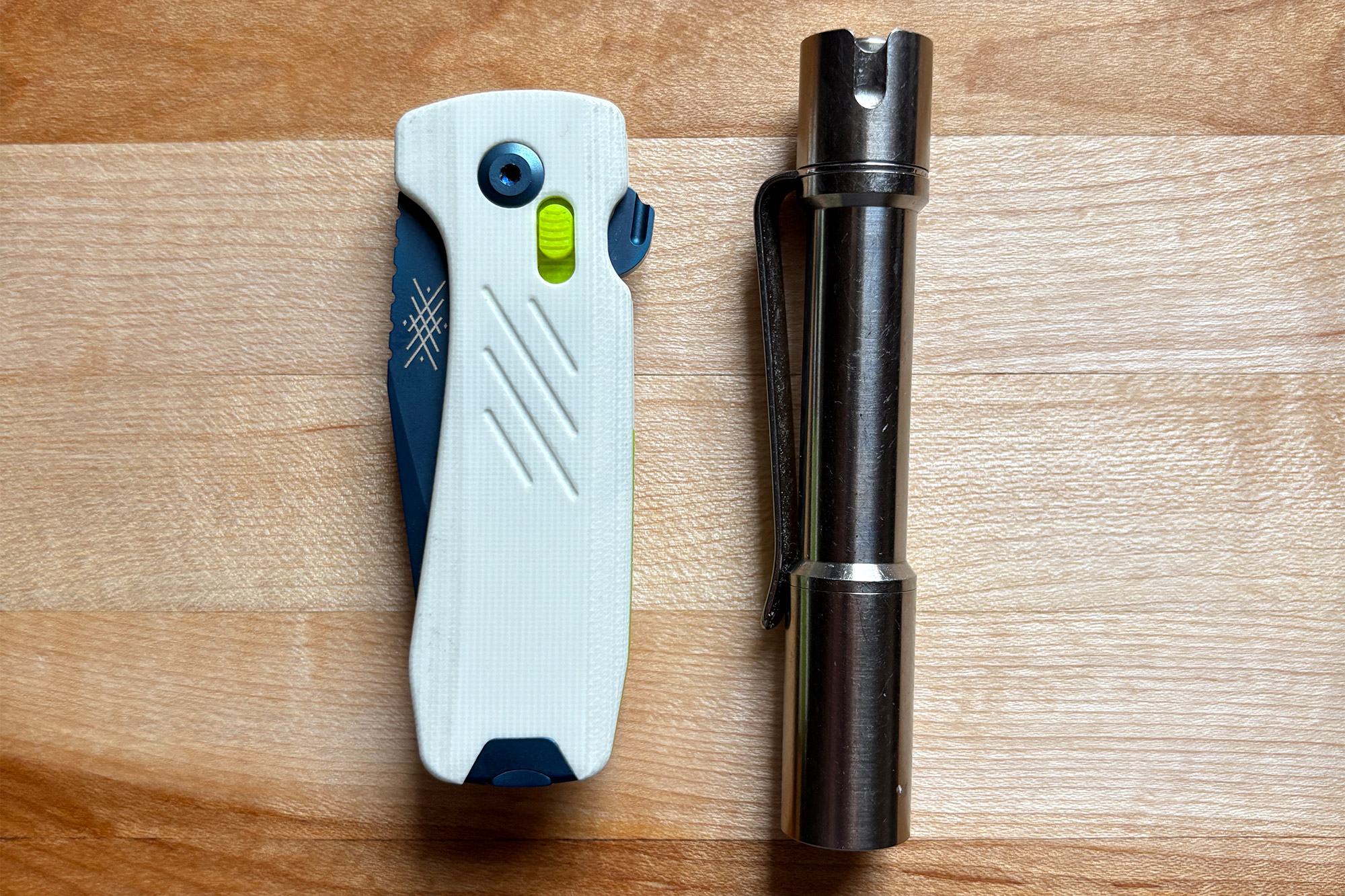 The Pepperwool Merino MM folded next to a silver flashlight