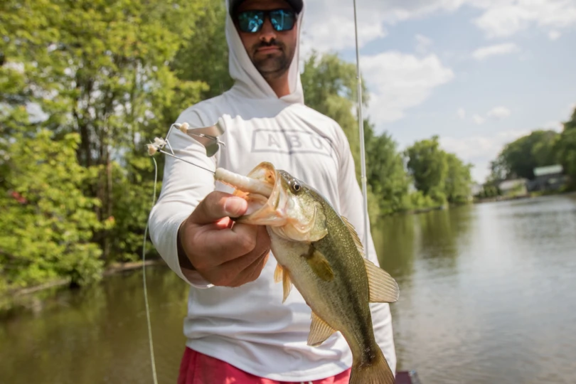 An angler holding a bass with the Berkley Riveter Buzzbait in it's mouth