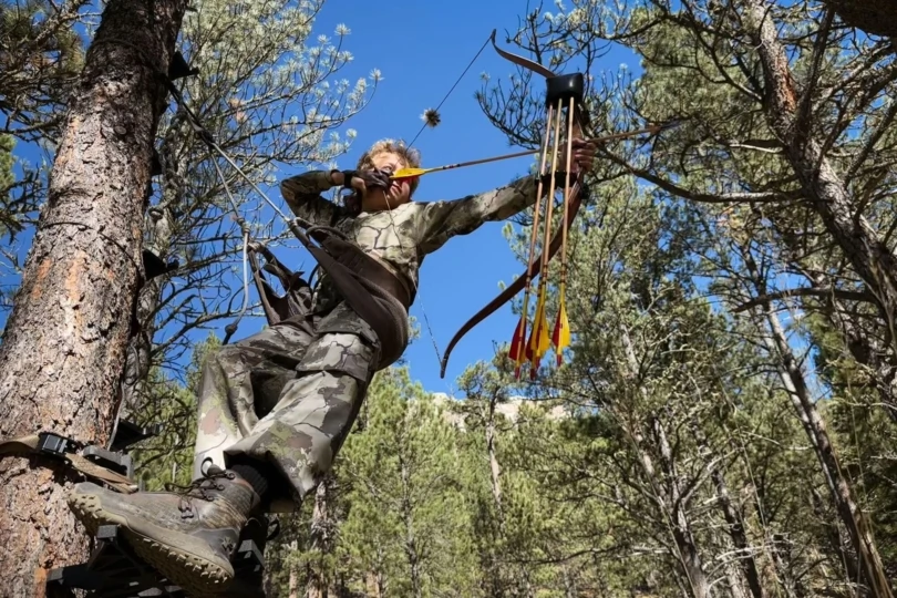 A traditional bow hunter drawing back while in a saddle.