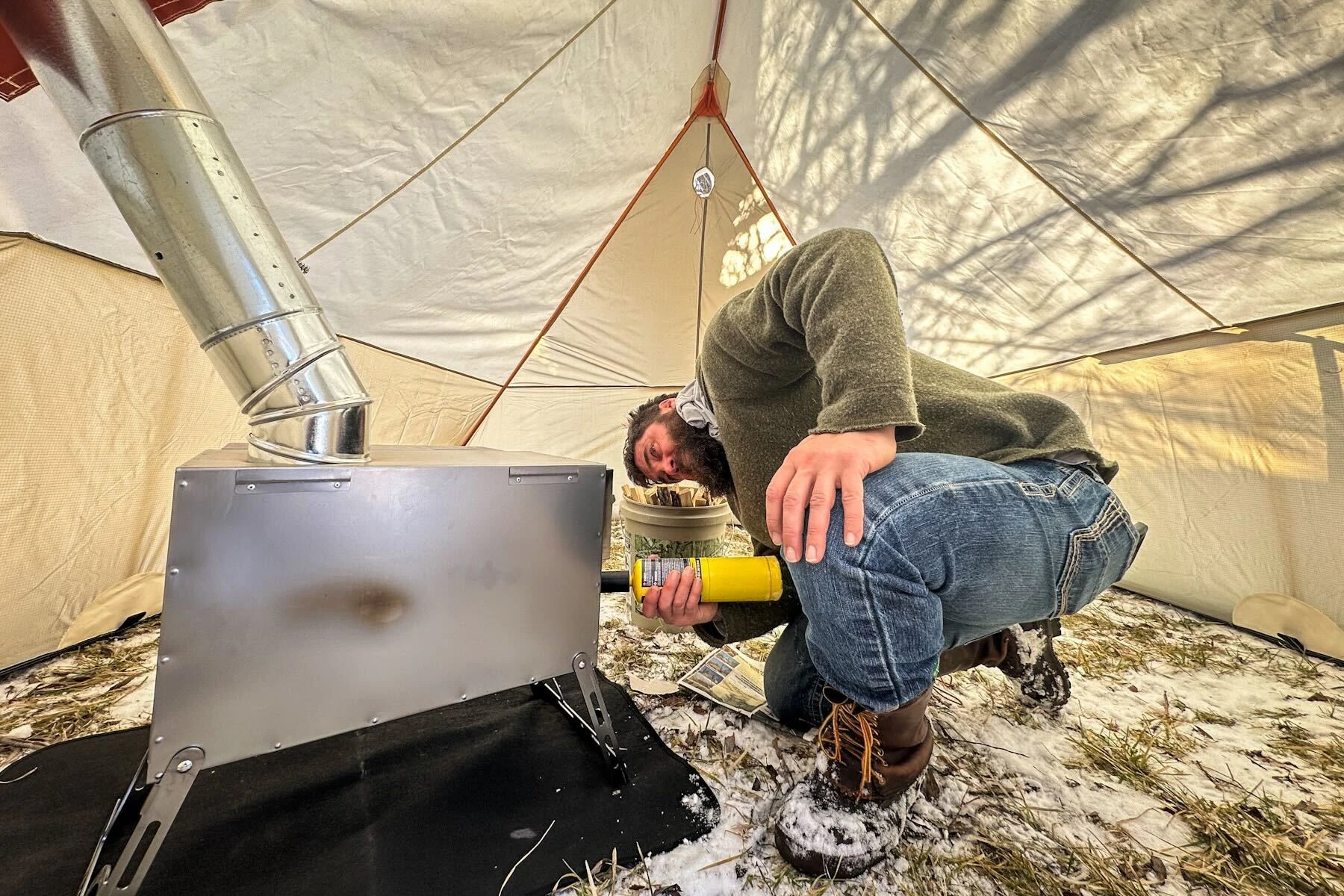A hunter starts a stove in a hunting tent.
