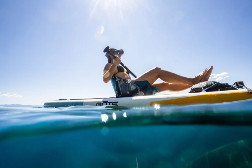 Person on paddleboard reclines in seat while out on the water.