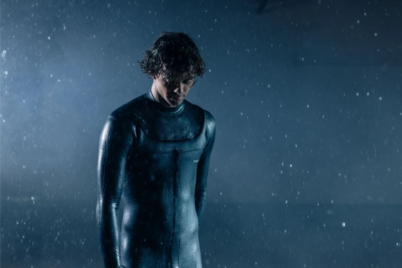 Hombre en traje de neopreno bajo lluvia