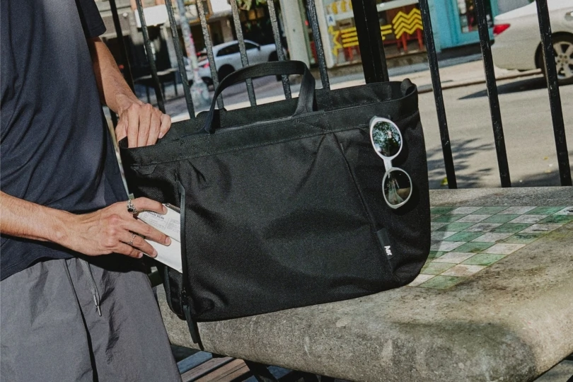 Toco de cerca de la persona que coloca la billetera en el bolsillo de una gran bolsa negra. 