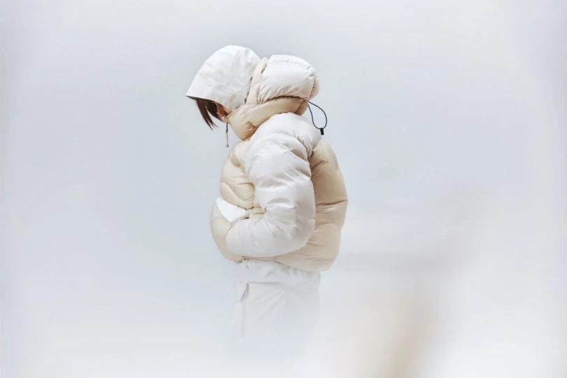 La persona usa una gran chaqueta blanca hinchada sobre fondo blanco. 