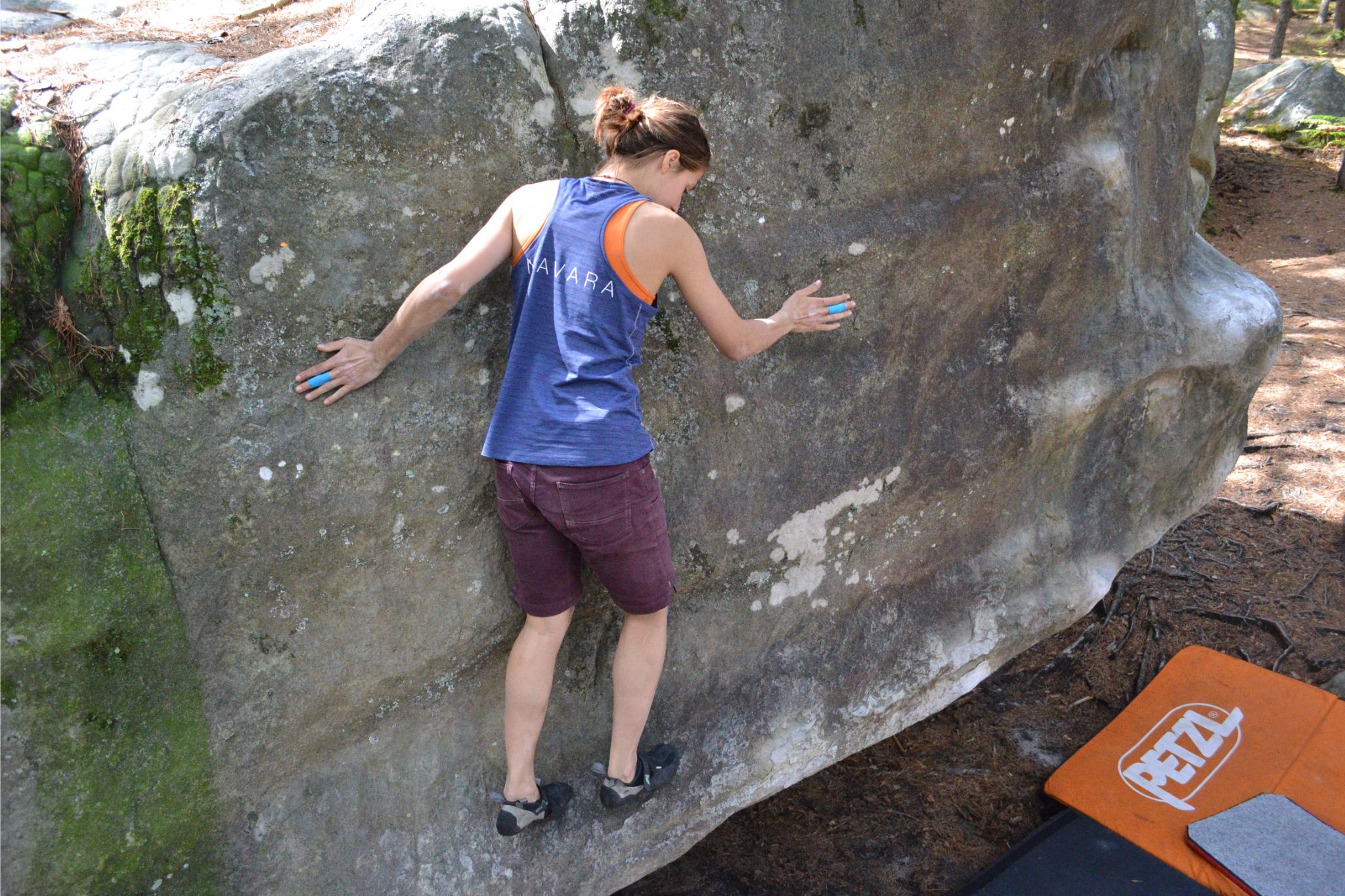 person climbs slab boulder outside with crash pad on ground