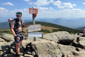 Hiker stands next to signs on trail