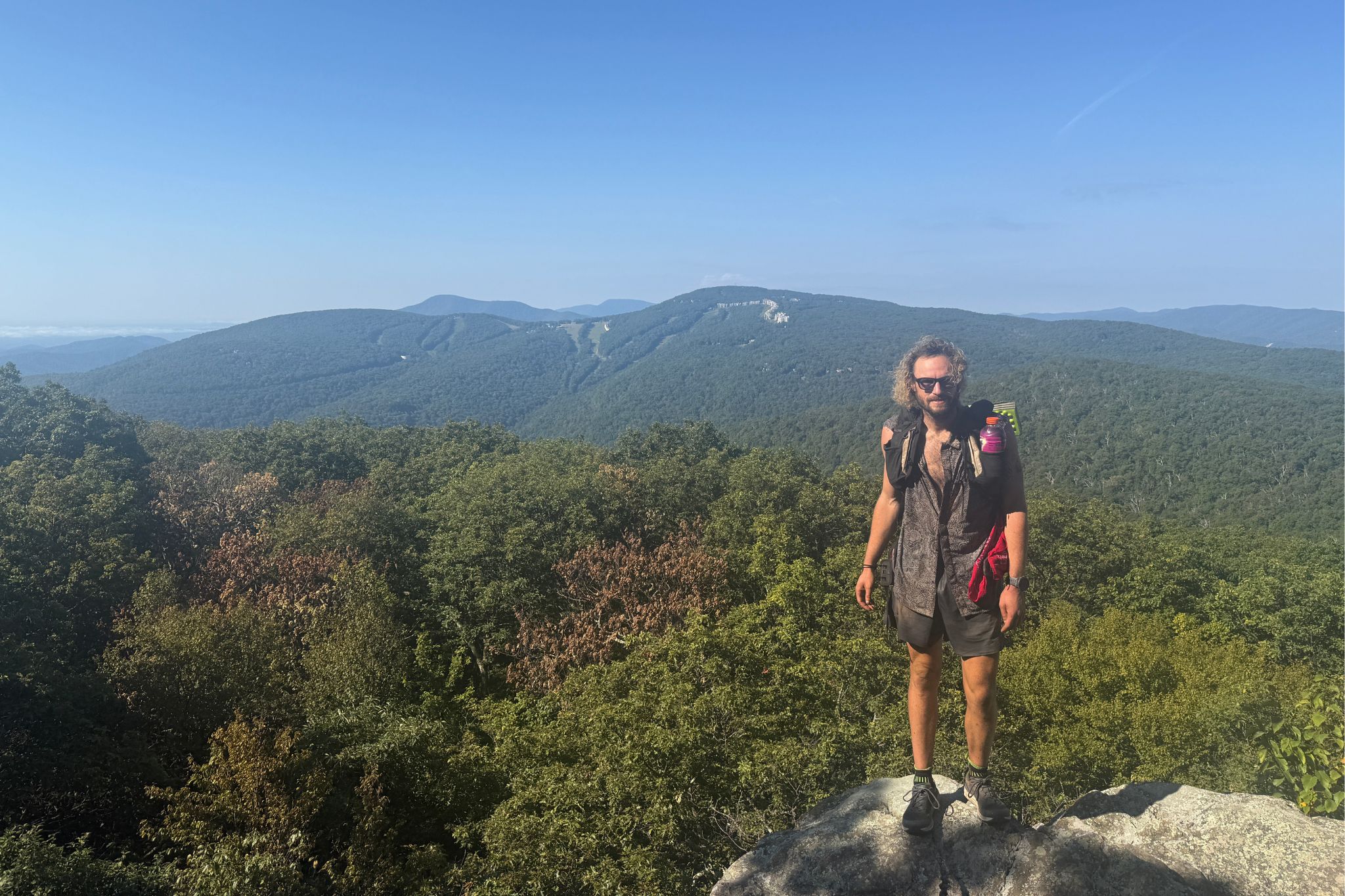 Hiker stands with mountains in background