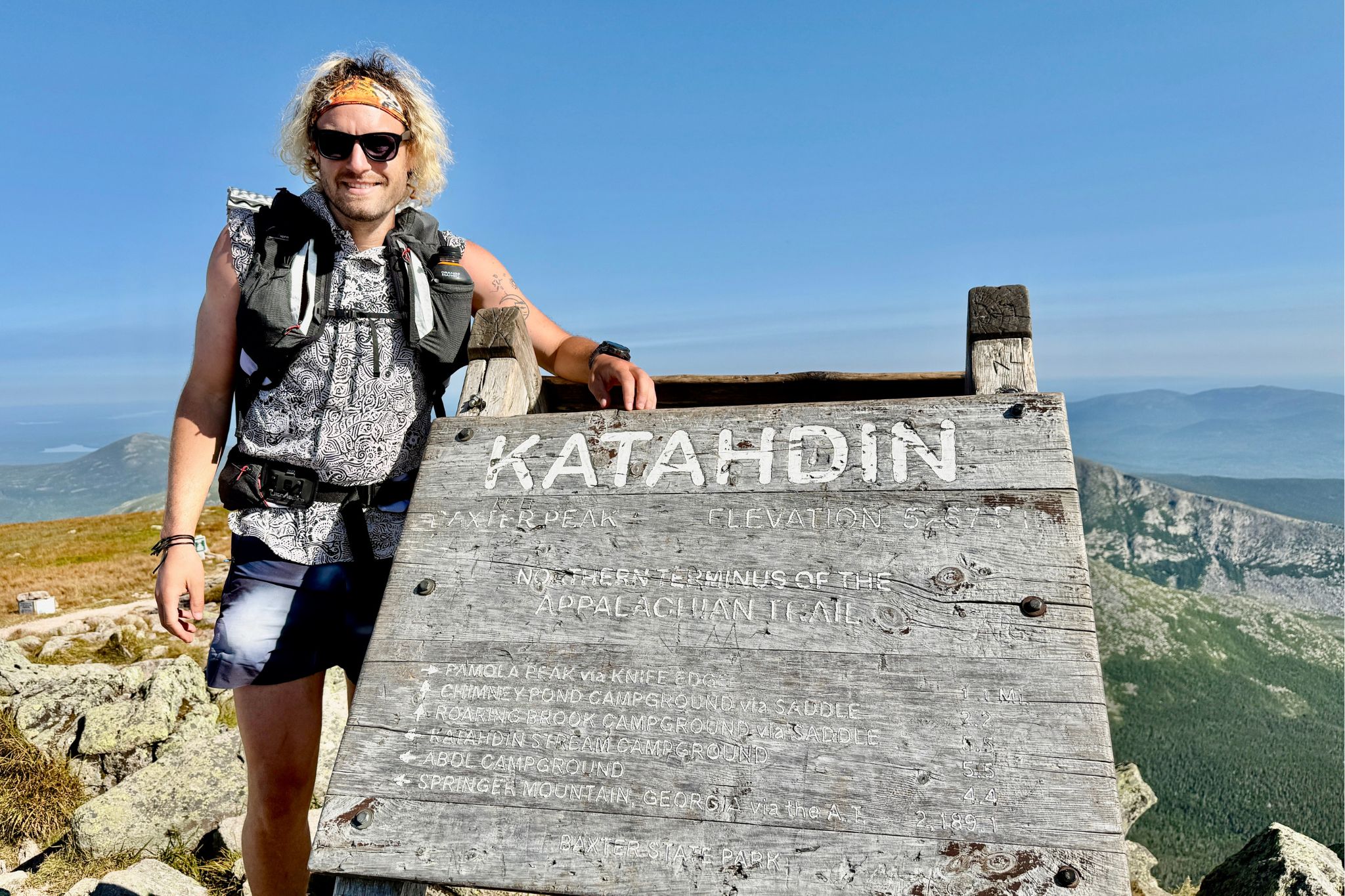 Hiker stands next to Katadin sign
