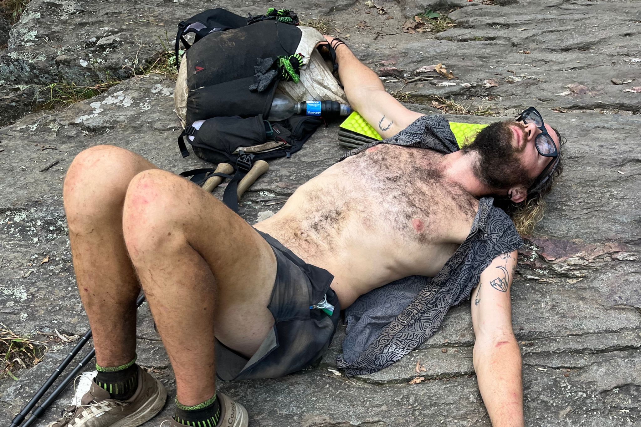 Shirtless man lays on trail exhausted.
