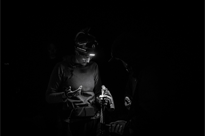 Trail runner stands in dark with headlamp