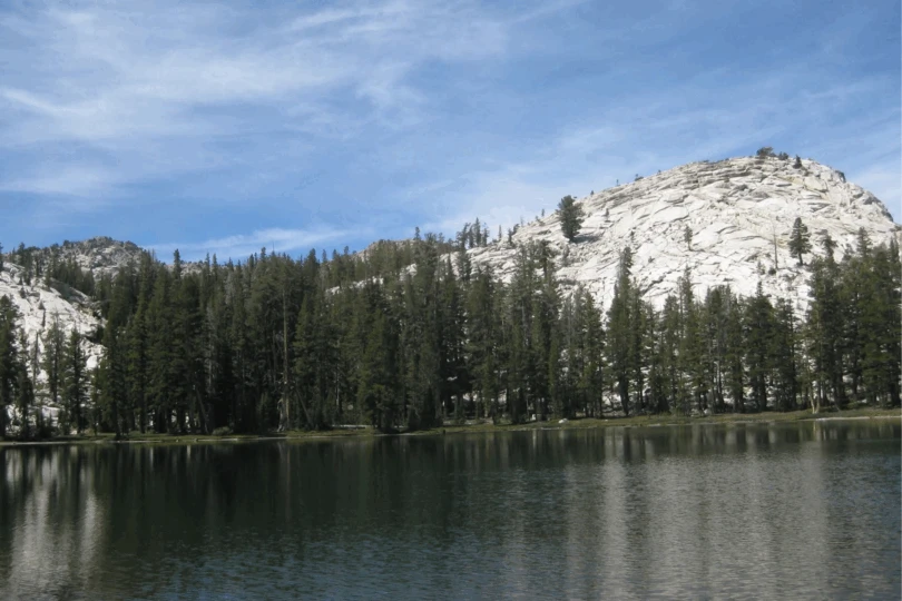 Lake in front of rocky mountain with trees.
