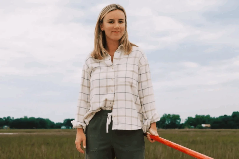Woman stands in field wearing white plaid flannel shirt