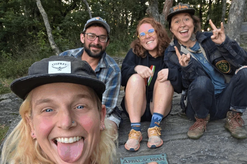 Four people smile in a selfie outdoors