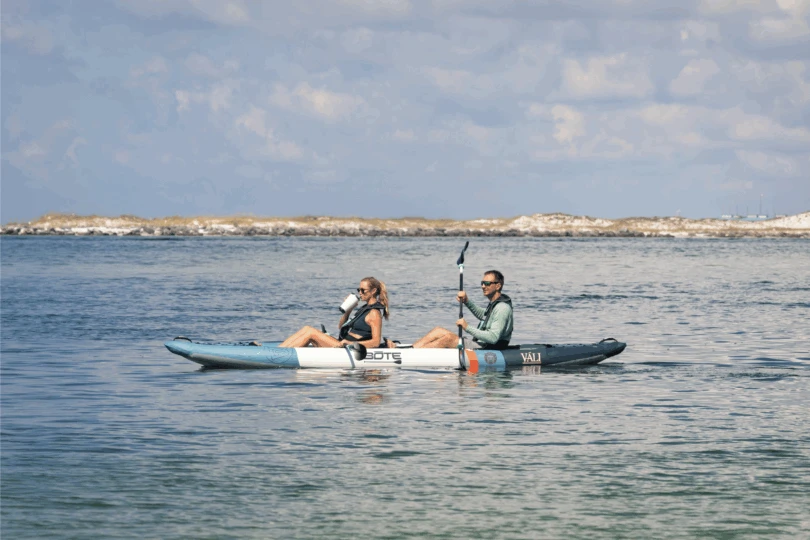 Dos personas se sientan en un kayak y reman en el agua.