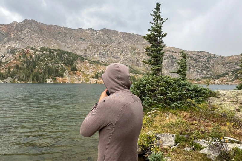 man wearing the Mountain Hardwear Airmesh Hoody by the lake, back view