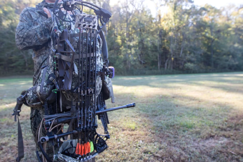 A bow strapped to a hunting backpack.