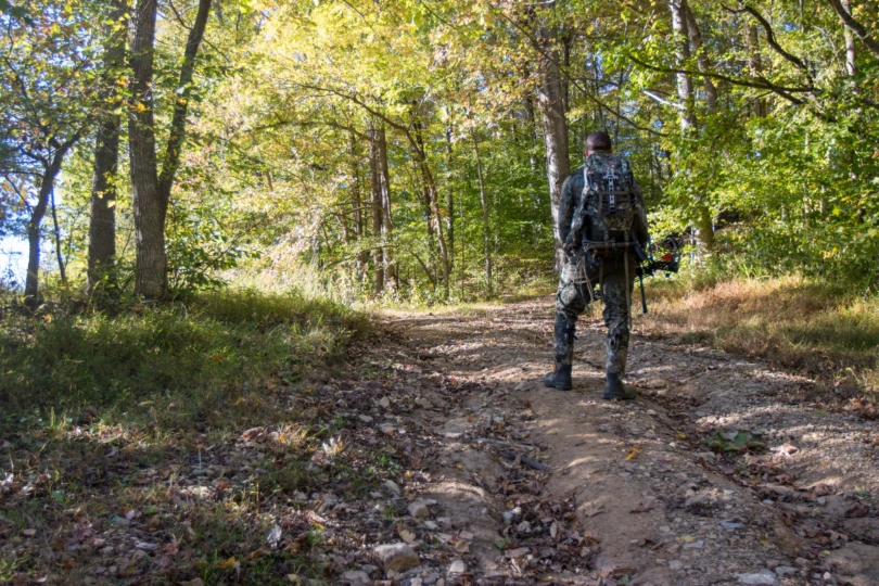 A hunter with a big game hunting pack on while hiking up a trail.