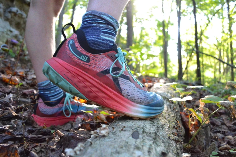 Close up shot of trail running shoes on log