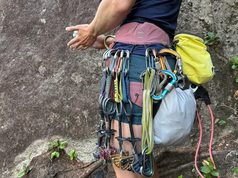 the author clips the papsura jacket to her climbing harness while climbing at smith rock state park