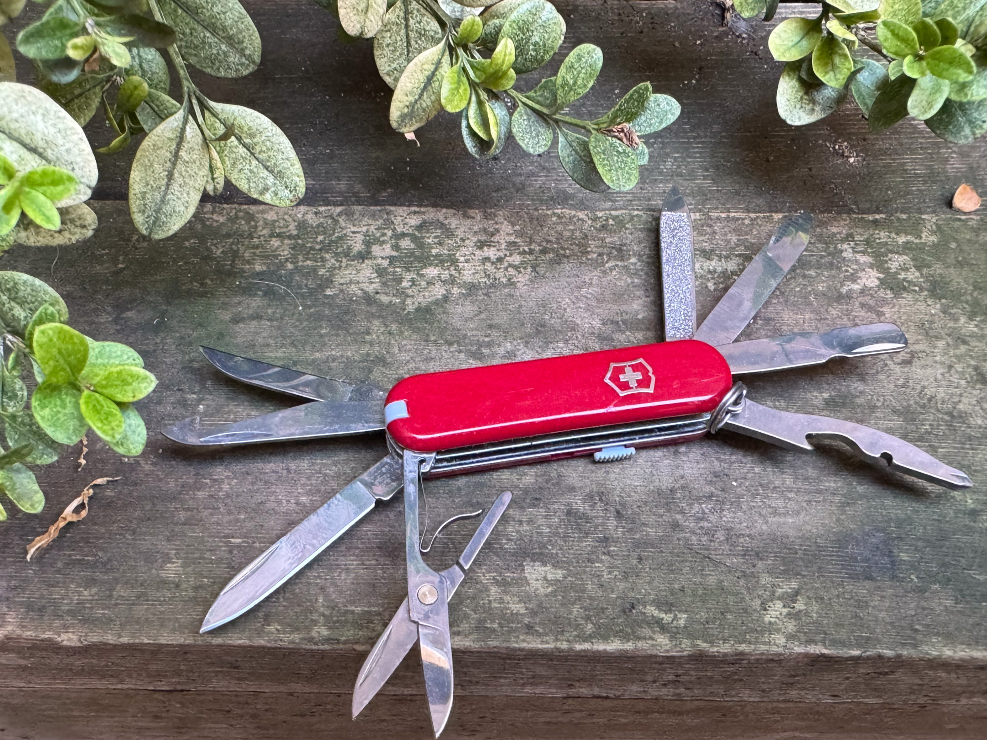 the mini champ multitool laying on a bench with all tools extended