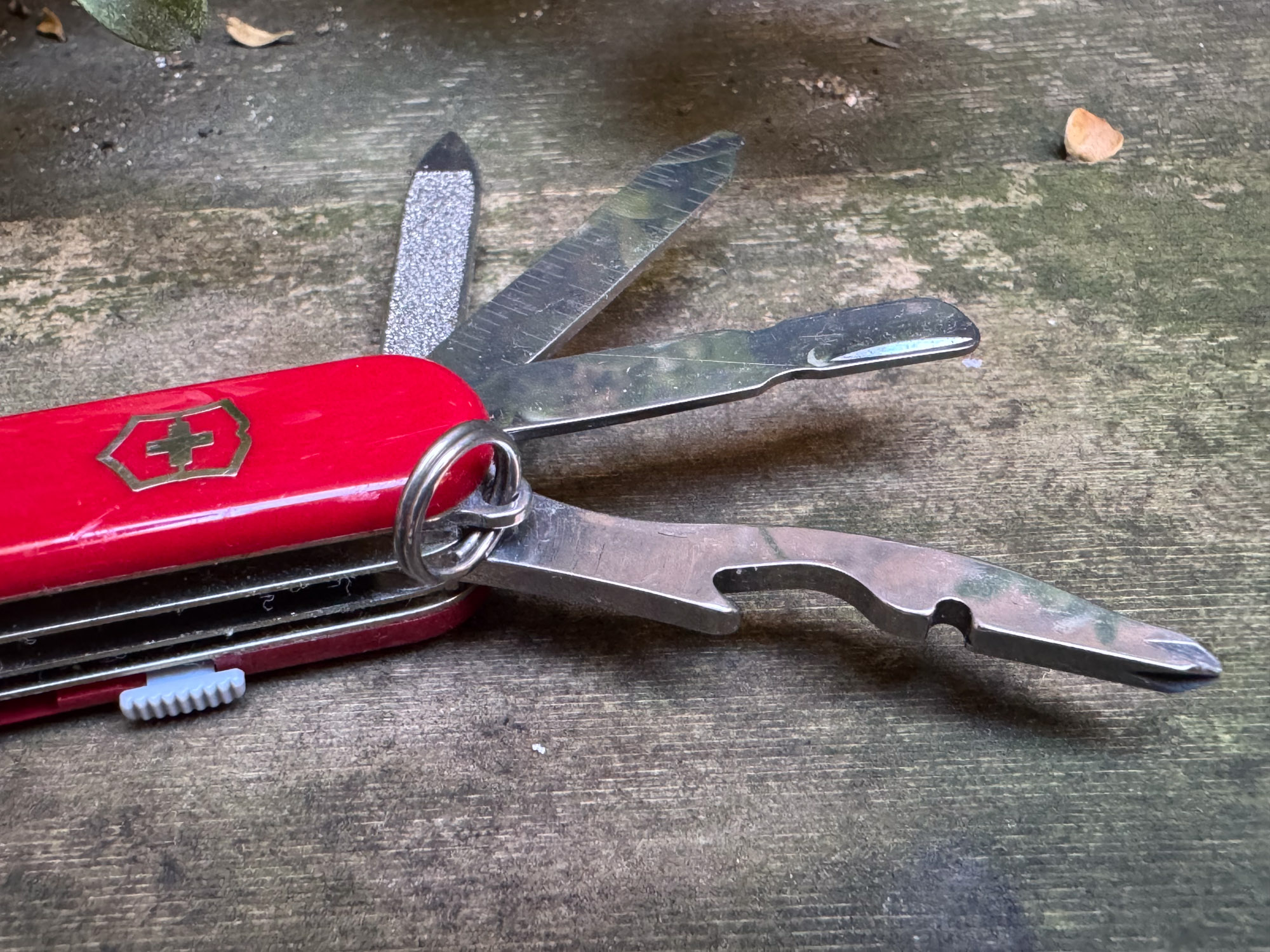 the mini champ swiss army knife with four tools spread out, including the cuticle pusher