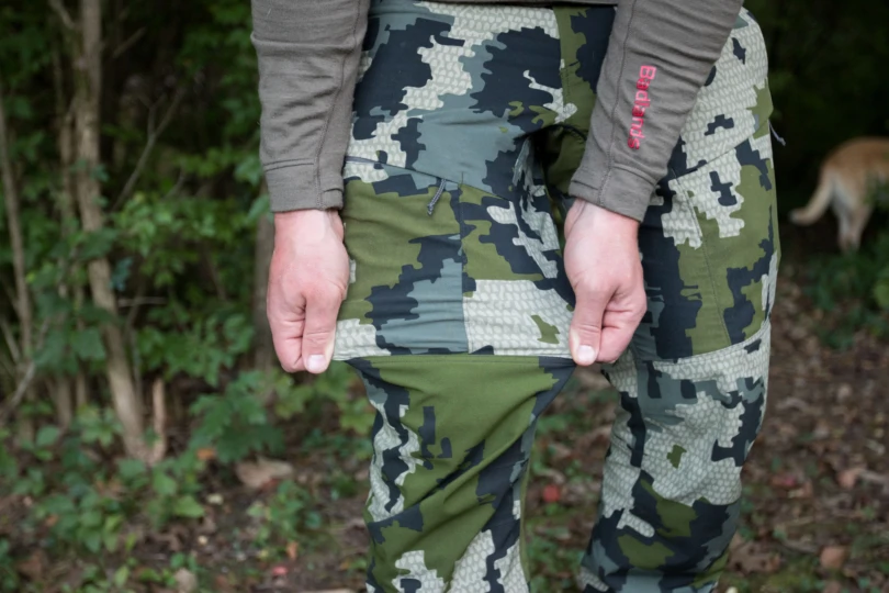 A person stretching the material of the KUIU Kutana Hybrid pants