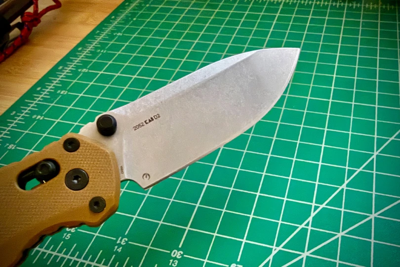 The knife blade is shown on a green cutting mat under indoor lighting