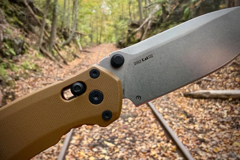 A close-up of the knife’s pivot and D2 steel marking taken on a forest trail