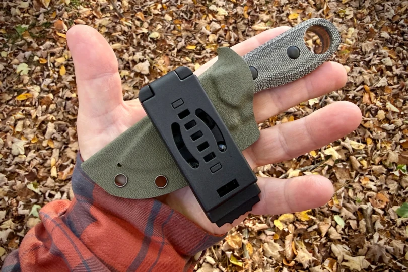 The Kizer Beaver Knife in its sheath resting in an open hand