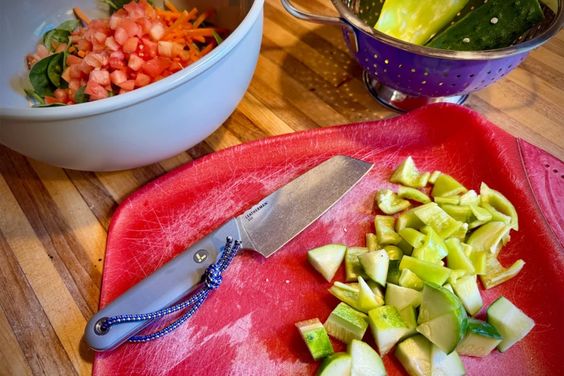 Leatherman Rustle lies on a red cutting board beside diced peppers