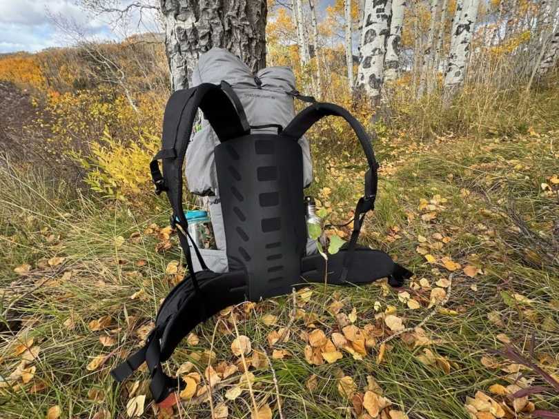 Outdoor Vitals Shadowlight 60 backpack resting upright against a tree, showing the back panel and straps