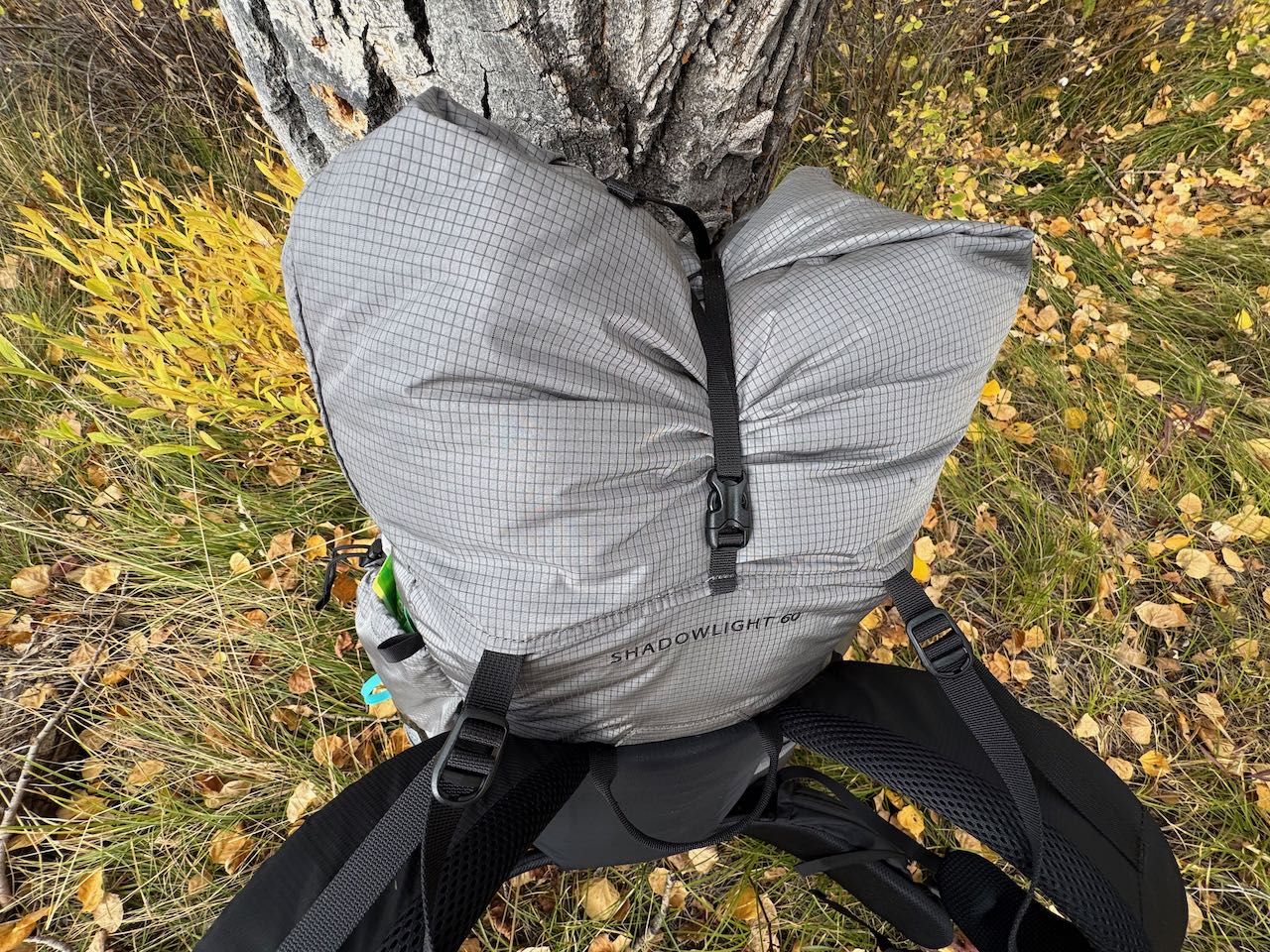 Top view of the Outdoor Vitals Shadowlight 60 leaning on a tree, showing the roll-top closure